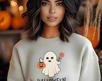 May include: A light gray sweatshirt with a cute cartoon ghost holding a jack-o-lantern and a flower. The text "HALLOWEEN" is printed below the ghost.