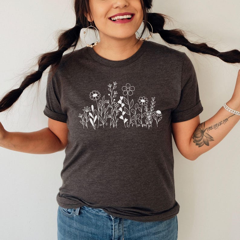 May include: A dark gray t-shirt with a white outline of a row of flowers and leaves. The flowers have simple, stylized shapes.