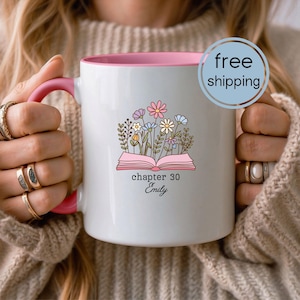 May include: White ceramic mug with a pink interior and handle. The mug features a floral design above an open book with the text "chapter 30 Emily". A blue circle with the words "free shipping" is visible.