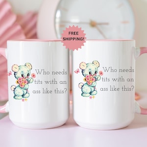May include: Two white ceramic mugs with pink handles and rims. Each mug features a cartoon bear holding flowers and the text "Who needs tits with an ass like this?" A pink starburst sticker reads "FREE SHIPPING!"