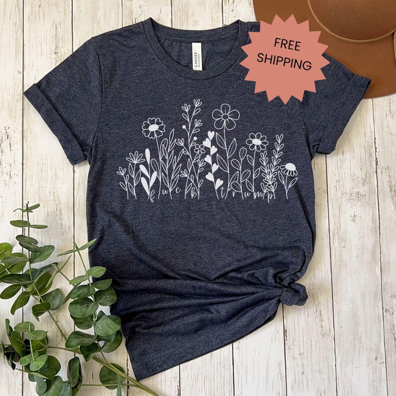May include: A dark gray t-shirt with a white design of stylized flowers and leaves. The design includes the text "It's true, I'm pretty."