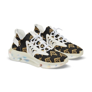 May include: Pair of black and gold sneakers with a repeating Masonic symbol pattern. The shoes have white laces and accents, and a clear sole with colorful speckles. The sneakers are designed for casual wear.