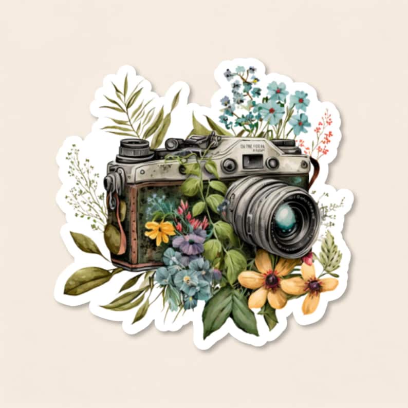 May include: A vintage-style camera sticker featuring a metallic body adorned with vibrant botanical elements including green leaves, blue forget-me-nots, and yellow flowers. The camera lens is prominent, surrounded by lush foliage and colourful floral accents.