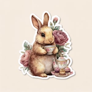 May include: A brown rabbit holding a small floral teacup, surrounded by pink roses and green leaves. Next to the rabbit is a matching floral teapot and a small plate with three colorful cupcakes, all presented as a die-cut sticker design.