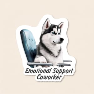Pu&ograve; includere: Un adesivo fustellato raffigurante un Siberian Husky bianco e nero con occhi azzurri brillanti seduto su una sedia da ufficio blu scuro. Il testo sotto il cane recita "Emotional Support Coworker" in un carattere sans-serif grigio scuro.