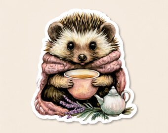 Può includere: Un'illustrazione adesiva di un riccio marrone e bianco avvolto in una sciarpa lavorata a maglia rosa polvere, che tiene in mano una piccola tazza da tè rosa. Accanto al riccio ci sono una teiera bianca e un rametto di lavanda viola.