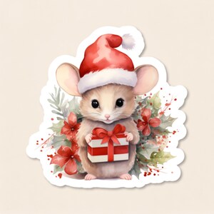 May include: A die-cut sticker featuring a small, light brown mouse wearing a red and white Santa hat. The mouse is holding a white gift box with red stripes and a red bow, surrounded by green holly leaves and red berries in a watercolor style.
