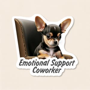 May include: A die-cut sticker featuring a small black and tan Chihuahua sitting in a dark brown leather chair. The dog has large ears and dark eyes. Below the dog, the text Emotional Support Coworker is printed in a dark grey sans-serif font.
