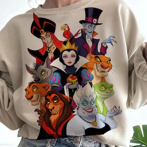 Puede incluir: Sudadera beige con un gr&aacute;fico colorido de villanos animados. El dise&ntilde;o incluye personajes como Jafar, la Reina Malvada, &Uacute;rsula y Scar. La obra de arte est&aacute; detallada con colores vibrantes e ilustraciones de estilo caricatura.