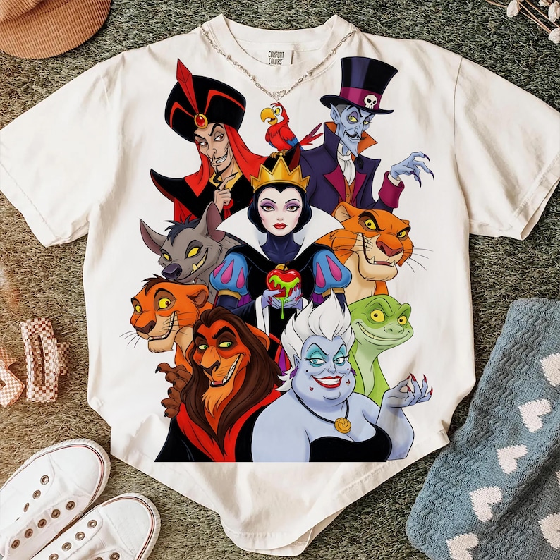 Puede incluir: Camiseta blanca con un gr&aacute;fico colorido de villanos de Disney, incluyendo Jafar, la Reina Malvada y &Uacute;rsula. El dise&ntilde;o presenta ilustraciones detalladas de los personajes, con colores vibrantes y contornos audaces. La camiseta es de material suave.