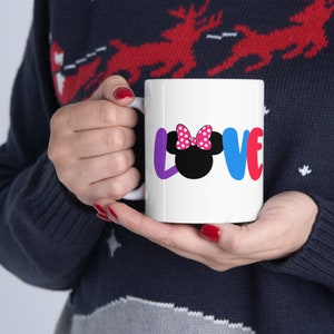 May include: White ceramic mug with a colorful "LOVE" graphic featuring a black and white Minnie Mouse head with a pink polka dot bow.