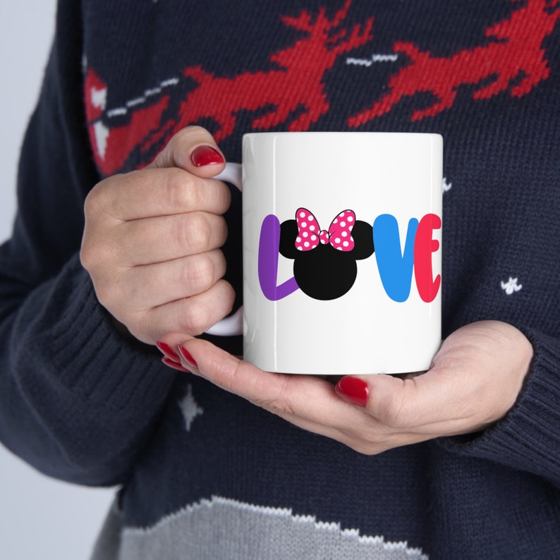 May include: White ceramic mug with a colorful "LOVE" graphic featuring a black and white Minnie Mouse head with a pink polka dot bow.