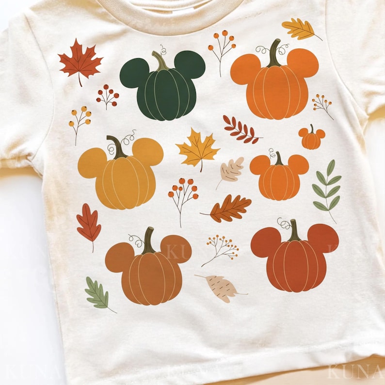 May include: Cream-colored t-shirt featuring a fall-themed design. The design includes pumpkins with mouse ears in various shades of orange, brown, and green, along with autumn leaves and berries. A festive and seasonal graphic.