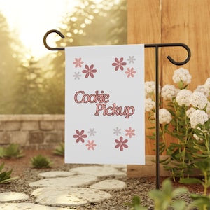 May include: A white garden flag with pink and gray flowers and the text "Cookie Pickup" in pink letters.