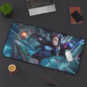 May include: A rectangular desk mat featuring a digital illustration of a character with long brown hair, wearing a blue and white suit with the text MEKA, holding a futuristic pink and black blaster, set against a blue and white light background.