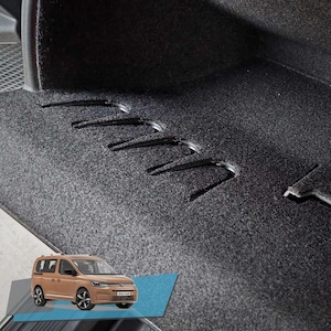 Può includere: Primo piano di un tappetino per auto grigio scuro con diversi ganci in metallo nero. Un'auto giocattolo color beige è posizionata nell'angolo in basso a sinistra. L'auto ha ruote nere e un portapacchi argentato.