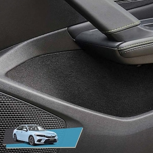 May include: A close-up of the interior of a car door. The door panel is black with a grey fabric insert. The door handle is black with green stitching detail. A small speaker is visible in the lower left corner of the image. A white car is shown in the lower right corner of the image.