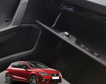 May include: A red car, a Seat Ibiza, is shown in the interior of a car. The car is parked in the passenger seat of a black car. The car's interior is black with a black dashboard and black seats.