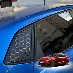 Könnte beinhalten: Ein blaues Auto mit einem Wabenmuster auf der Heckscheibe. Ein rotes Auto befindet sich in der unteren rechten Ecke. Das Fenster des Autos hat einen schwarzen Rahmen. Das Wabenmuster ist weiß und grau.