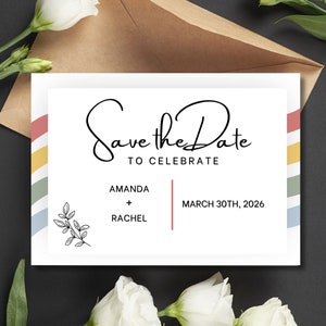 Peut inclure: Carte "Save the Date" avec une bordure à rayures arc-en-ciel. La carte indique "Save the Date" avec le texte "To Celebrate" en dessous. Les noms Amanda et Rachel sont listés avec un signe plus entre eux. La date du 30 mars 2026 est indiquée en dessous.