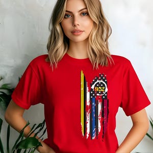 May include: A red t-shirt with a graphic of a thin blue line flag with a black and yellow stripe and a circle with the number 922 in it.