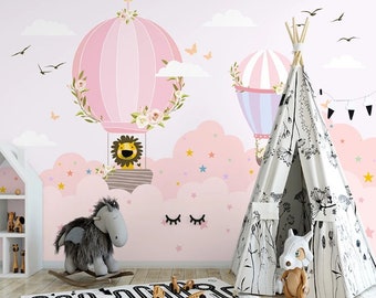 Könnte beinhalten: Ein rosa-weißer Heißluftballon mit einem Löwen darin, umgeben von Wolken und Sternen. Im Vordergrund steht ein weißes Tipi-Zelt mit schwarzen Blumenmustern. Der Hintergrund ist eine hellrosa Wand mit einem weißen Wolkenmuster.