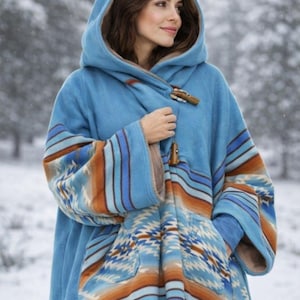 May include: A blue hooded poncho with a Southwestern-inspired pattern in shades of orange, blue, and white. The poncho features a toggle closure and is made of a soft, warm material, perfect for cold weather.