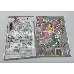 May include: A clear plastic package containing a set of clear rubber stamps with floral and book-themed designs. The stamps are arranged in a grid pattern and include phrases like "The End Chapter", "Today's Story", "Read More", "Book My Time", "What's Next", and "Fill the Page".