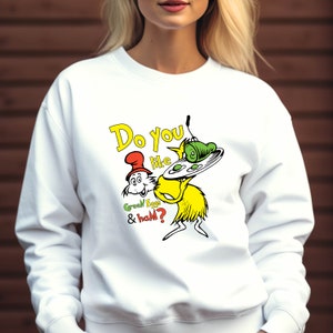 May include: White sweatshirt with a green and yellow cartoon character holding a plate of green eggs and ham. The text "Do you like green eggs & ham?" is printed on the shirt.