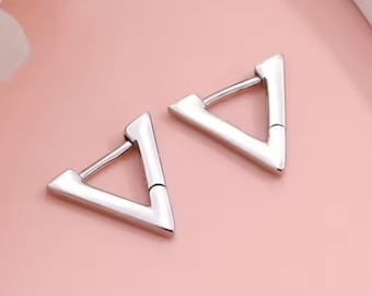 May include: A pair of silver triangle hoop earrings. The earrings are simple and modern in design.