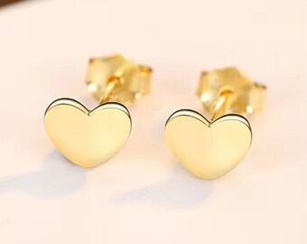 May include: A pair of gold heart-shaped stud earrings. The earrings are small and delicate, and they would make a great gift for someone special.