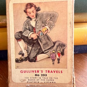May include: A rectangular card game box titled Gulliver's Travels No 293. The front features an illustration of a person in 18th-century attire with small figures in their pocket and on the ground. Text includes Piatnik Vienna and Made in Austria.