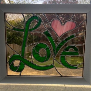 May include: A stained glass window with the word "LOVE" in green letters and a pink heart in the center.
