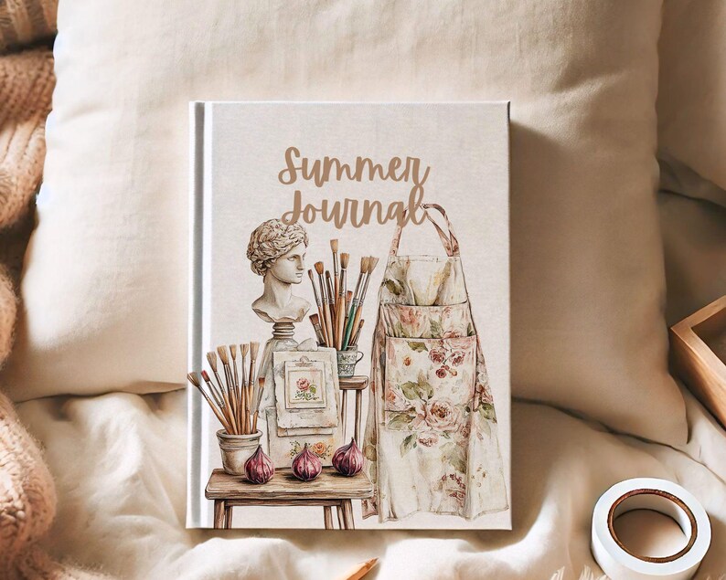 Puede incluir: Un diario de tapa dura con las palabras "Summer Journal" en escritura dorada. La portada presenta una ilustraci&oacute;n de acuarela de un delantal de artista, pinceles, un busto y otros &uacute;tiles de arte. El diario est&aacute; sobre una superficie color crema.