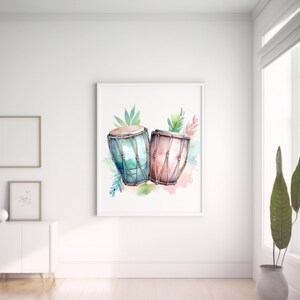 K&ouml;nnte beinhalten: Ein Aquarellbild von zwei Trommeln mit gr&uuml;nen Bl&auml;ttern und rosa und blauen Aquarellspritzer. Die Trommeln sind braun mit einem hellblauen und rosa Design.