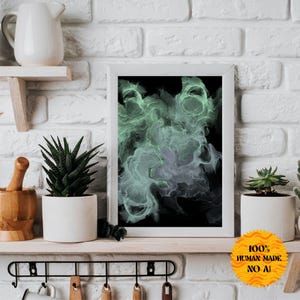 Könnte beinhalten: Ein gerahmter abstrakter Kunstdruck mit wirbelnden grünen und grauen Formen auf schwarzem Hintergrund. Der Rahmen ist weiß und der Druck trägt den Titel "100% Human Made No AI".