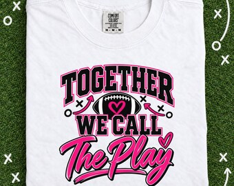 May include: A white t-shirt featuring a graphic design with the text TOGETHER WE CALL THE PLAY in black and pink lettering. The design includes a football illustration with a pink heart in the center and various play-calling symbols like arrows and x's.
