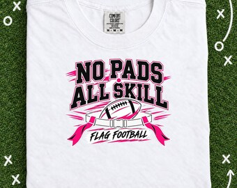 May include: A white t-shirt featuring a graphic with the text NO PADS ALL SKILL and FLAG FOOTBALL in black and pink lettering. The design includes a football illustration and a flag football belt with pink flags on a white background.