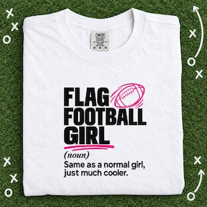 Puede incluir: Una camiseta blanca con el texto negro FLAG FOOTBALL GIRL, un gráfico de balón de fútbol americano rosa y la definición (noun) Same as a normal girl, just much cooler. La camiseta tiene una etiqueta de Comfort Colors en el cuello.
