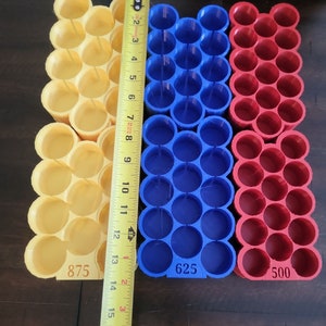 May include: Three 3D printed battery storage containers, one yellow, one blue, and one red. The containers are labeled with the numbers 875, 625, and 500.