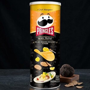 May include: A cylindrical Pringles snack container featuring a yellow top section with the Chef Morgan logo and a black lower section. The label displays the text Pringles Black Truffle Velvet Mashed Potatoes Flavor, potato crisps, and truffles.
