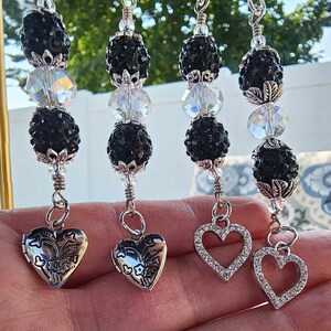 May include: Four silver charm necklaces with black and clear crystal beads and a heart-shaped pendant. Each necklace has a different heart pendant.