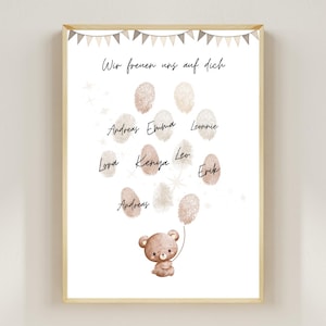 Puede incluir: Impresión enmarcada con un marco de madera clara. La impresión presenta un oso de peluche sosteniendo un globo hecho de huellas dactilares. El texto "Wir freuen uns auf dich" está en la parte superior, con nombres debajo.