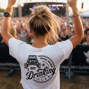 May include: A white t-shirt with a black graphic of an off-road vehicle and the text "Official Member 1 Day Drinking Club".