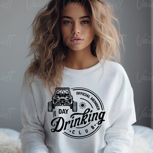 May include: White sweatshirt with a black and white graphic of an off-road vehicle and the text "Official Member 1 Day Drinking Club".