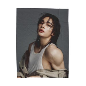 Puede incluir: Un retrato de estudio presenta a una persona con cabello oscuro y una camiseta sin mangas blanca. La persona lleva una chaqueta beige. El fondo es de color gris liso.