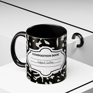 Puede incluir: Una taza de cerámica en blanco y negro con un patrón clásico de cuaderno de composición. El frente muestra una etiqueta blanca con el texto COMPOSITION BOOK y el texto manuscrito Subject: Coffee. La taza tiene un asa y un interior negros.