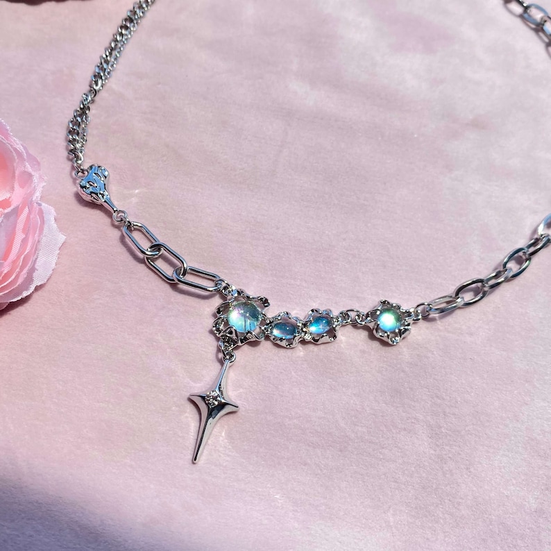 Op de afbeelding: Een zilveren ketting met een ster hanger en drie iriserende blauwe stenen gezet in zilver.