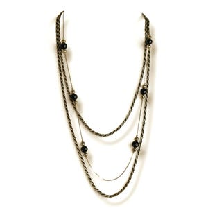 May include: A multi-strand necklace featuring two twisted metallic gold-tone rope chains and a thin, smooth gold-tone chain. The design is accented with evenly spaced, polished black spherical beads and smaller gold-tone spacer beads.