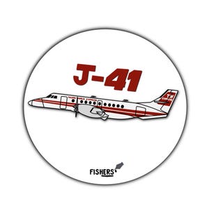 May include: A white airplane with red accents and the text "J-41" on the side. The airplane is labeled "Trans World Express" and "Twin Express". The image is a round sticker with the text "Fishers" at the bottom.